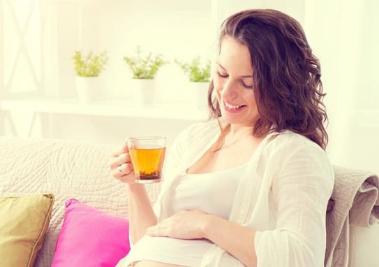 Mẹ bầu đang uống trà thảo mộc (ginger tea) nhẹ nhàng, gợi ý thức uống an toàn 3 tháng đầu.